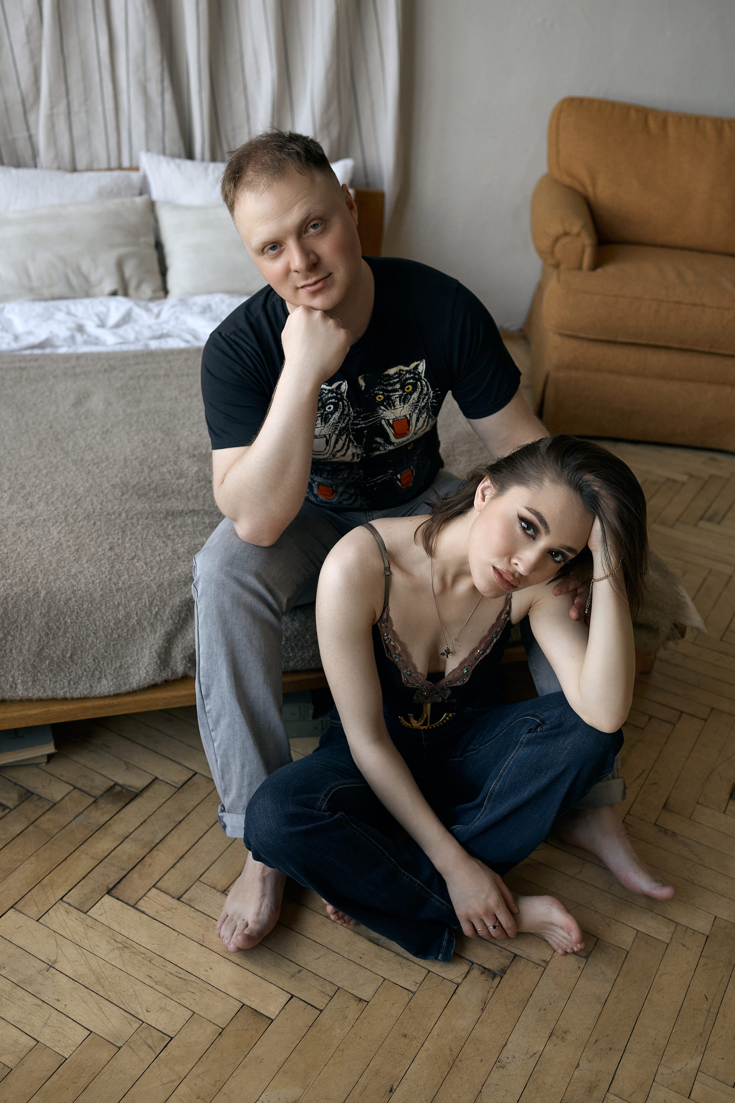 Мужчина сидит на кровати, женщина у его ног на полу